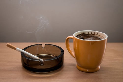Cigarette in ashtray plus a mug of coffee