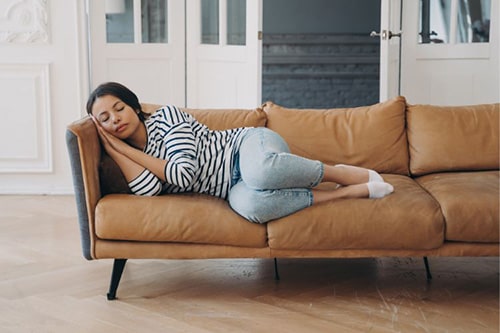 Woman having a nap on brown leather cough